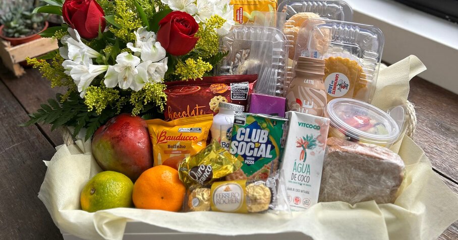 Cesta de café da manhã com rosas, frutas e itens de padaria